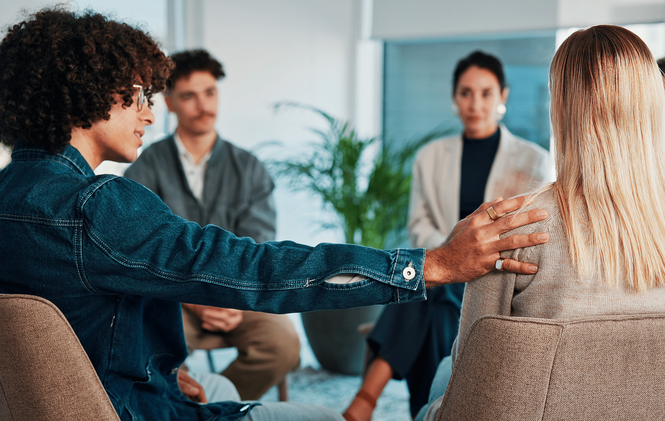 Eine Gruppe von Personen in einem Gespräch. Eine Person legt eine Hand auf die Schulter einer anderen Person. Eine Gruppe von Personen in einem Gespräch. Eine Person legt eine Hand auf die Schulter einer anderen Person.