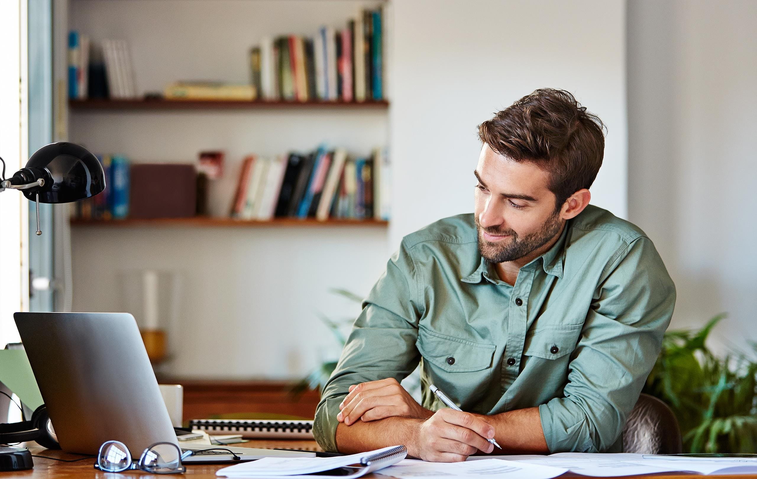 Mann sitzt am Schreibtisch und sucht nach Pensionskasse Mann sitzt am Schreibtisch und sucht nach Pensionskasse
