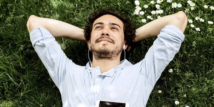 Man lies on meadow, looks into the sky and listens to music. Man lies on meadow, looks into the sky and listens to music.